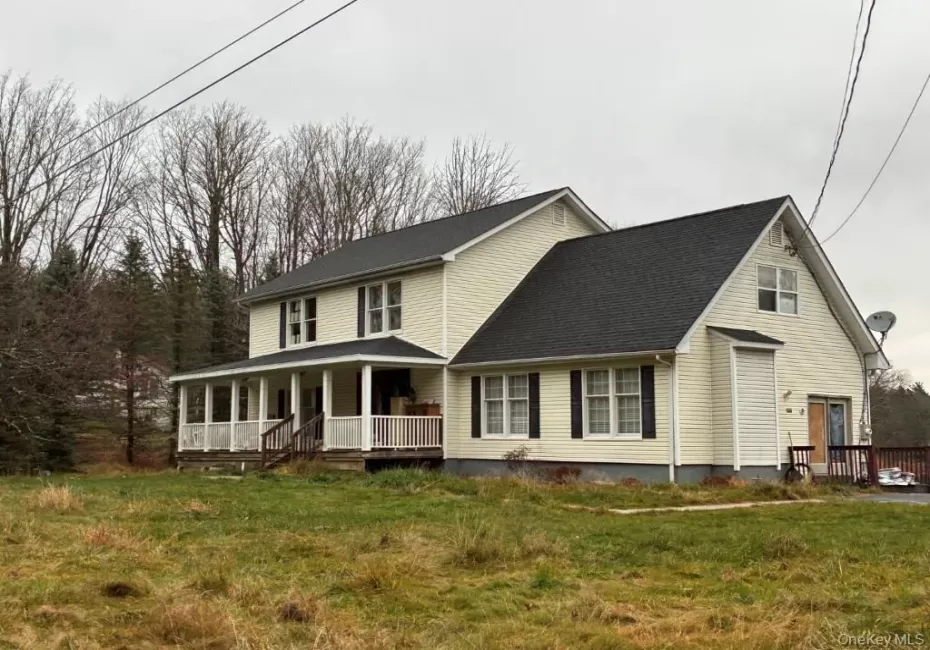 View of front facade with a front yard, covered porch, and roof with shingles View of front facade with a front yard, covered porch, and roof with shingles