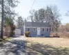 Single story home featuring aphalt driveway, fence, a detached garage, a front lawn, and an outbuilding Single story home featuring aphalt driveway, fence, a detached garage, a front lawn, and an outbuilding