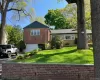 Split-level residence featuring a brick and stone facade, attached garage, and a sloped, manicured lawn Split-level residence featuring a brick and stone facade, attached garage, and a sloped, manicured lawn