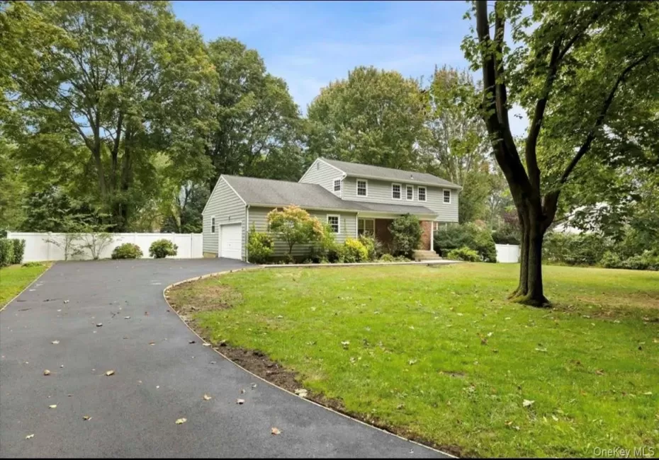 Traditional-style house with driveway, an attached garage, and view of scattered trees Traditional-style house with driveway, an attached garage, and view of scattered trees