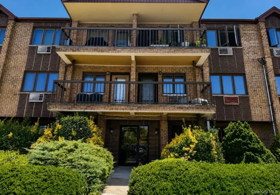 Brick facade building with balconies, dark framed windows, and mature landscaping Brick facade building with balconies, dark framed windows, and mature landscaping