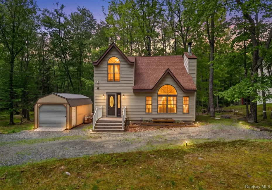 Modern rustic home featuring a light-colored exterior, an arched window, and a dark brown shingle roof Modern rustic home featuring a light-colored exterior, an arched window, and a dark brown shingle roof