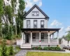 Two-story residence featuring a covered front porch with white columns, light gray siding, dark trim, and a gabled roofline Two-story residence featuring a covered front porch with white columns, light gray siding, dark trim, and a gabled roofline