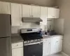 Kitchen featuring white shaker-style cabinetry, a stainless steel gas range with a matching range hood, and a stainless steel refrigerator Kitchen featuring white shaker-style cabinetry, a stainless steel gas range with a matching range hood, and a stainless steel refrigerator