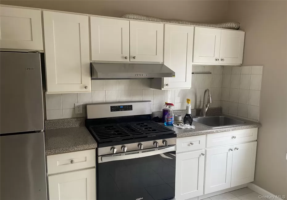 Kitchen featuring white shaker-style cabinetry, a stainless steel gas range with a matching range hood, and a stainless steel refrigerator Kitchen featuring white shaker-style cabinetry, a stainless steel gas range with a matching range hood, and a stainless steel refrigerator