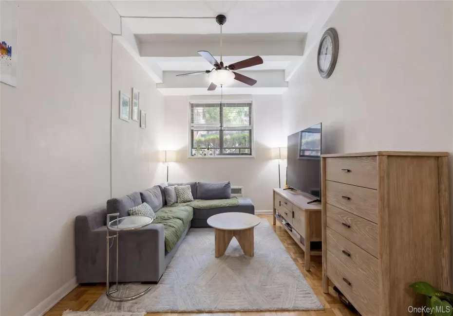 Living space featuring 10 foot ceilings, wood-finish flooring and a ceiling fan Living space featuring 10 foot ceilings, wood-finish flooring and a ceiling fan
