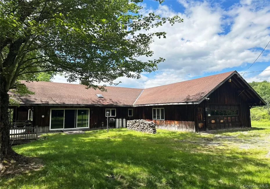 Front exterior featuring rustic western-inspired architecture, expansive attached garage, deck, and natural wooded surroundings. Front exterior featuring rustic western-inspired architecture, expansive attached garage, deck, and natural wooded surroundings.