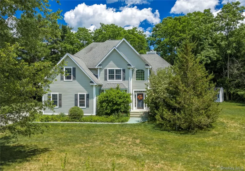 Two-story residence featuring light gray siding with dark shutters, multiple gables, and a prominent front entry with an arched window above Two-story residence featuring light gray siding with dark shutters, multiple gables, and a prominent front entry with an arched window above