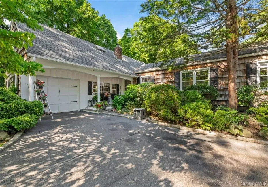 Charming exterior with cedar shake siding, a covered entry porch, and an attached garage Charming exterior with cedar shake siding, a covered entry porch, and an attached garage