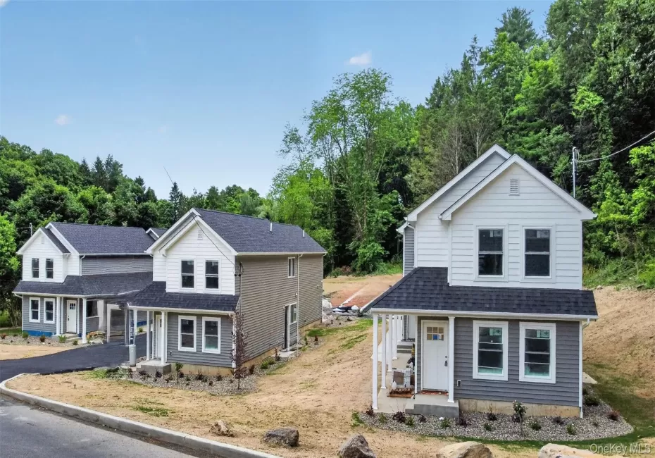 Newly constructed two-story residence featuring a covered front porch, white trim, and a dark shingle roof Newly constructed two-story residence featuring a covered front porch, white trim, and a dark shingle roof