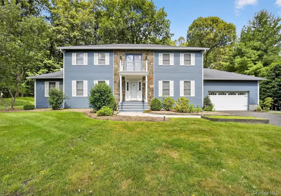 View of front facade with asphalt driveway, a balcony, an attached garage, and a front lawn View of front facade with asphalt driveway, a balcony, an attached garage, and a front lawn