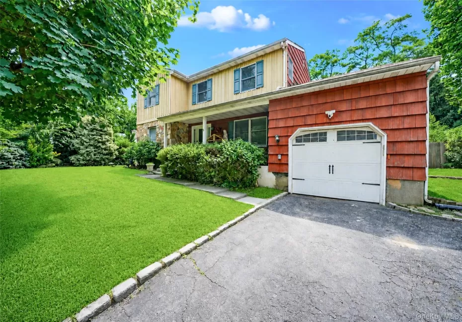 Exterior featuring a stone facade, red shingle siding, and a white garage door with decorative hardware Exterior featuring a stone facade, red shingle siding, and a white garage door with decorative hardware