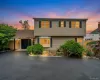 Multi-level residence featuring a bay window, dark shutters, and a prominent asphalt driveway Multi-level residence featuring a bay window, dark shutters, and a prominent asphalt driveway