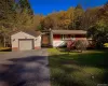View of front facade featuring an outdoor structure, a front lawn, driveway, and a chimney View of front facade featuring an outdoor structure, a front lawn, driveway, and a chimney