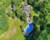Expansive property featuring a large in-ground pool, extensive paved patio, substantial green space, mature trees, and a detached storage shed Expansive property featuring a large in-ground pool, extensive paved patio, substantial green space, mature trees, and a detached storage shed