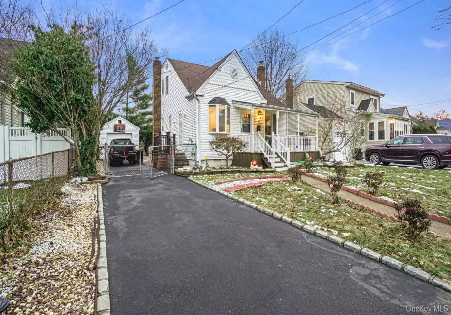 View of front of home with a gate, a chimney, driveway, covered porch, and fence View of front of home with a gate, a chimney, driveway, covered porch, and fence
