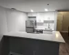 Contemporary kitchen featuring white shaker cabinetry, stainless steel appliances, a subway tile backsplash, and light-tone countertops Contemporary kitchen featuring white shaker cabinetry, stainless steel appliances, a subway tile backsplash, and light-tone countertops