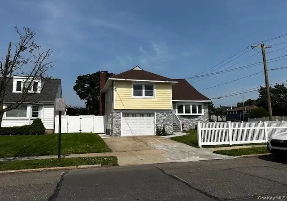 View of front of home with stone siding, a garage, driveway, a gate, and a chimney View of front of home with stone siding, a garage, driveway, a gate, and a chimney