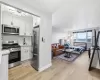 Kitchen featuring stainless steel appliances, white cabinetry, open floor plan, light wood-type flooring, and light stone counters Kitchen featuring stainless steel appliances, white cabinetry, open floor plan, light wood-type flooring, and light stone counters