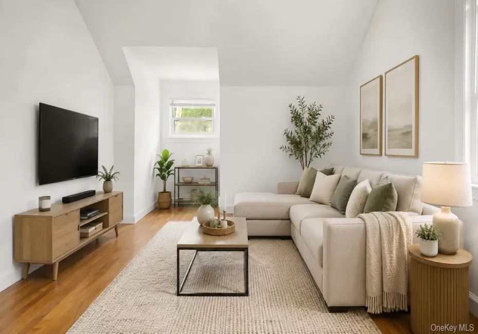 Living area featuring wood-finish flooring, white walls, and a prominent window Living area featuring wood-finish flooring, white walls, and a prominent window