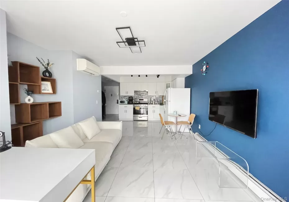 Living area with a baseboard radiator, light marble finish floors, and a wall mounted AC Living area with a baseboard radiator, light marble finish floors, and a wall mounted AC