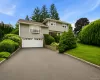 Split-level residence featuring light-colored siding and a two-car garage with white paneled doors Split-level residence featuring light-colored siding and a two-car garage with white paneled doors
