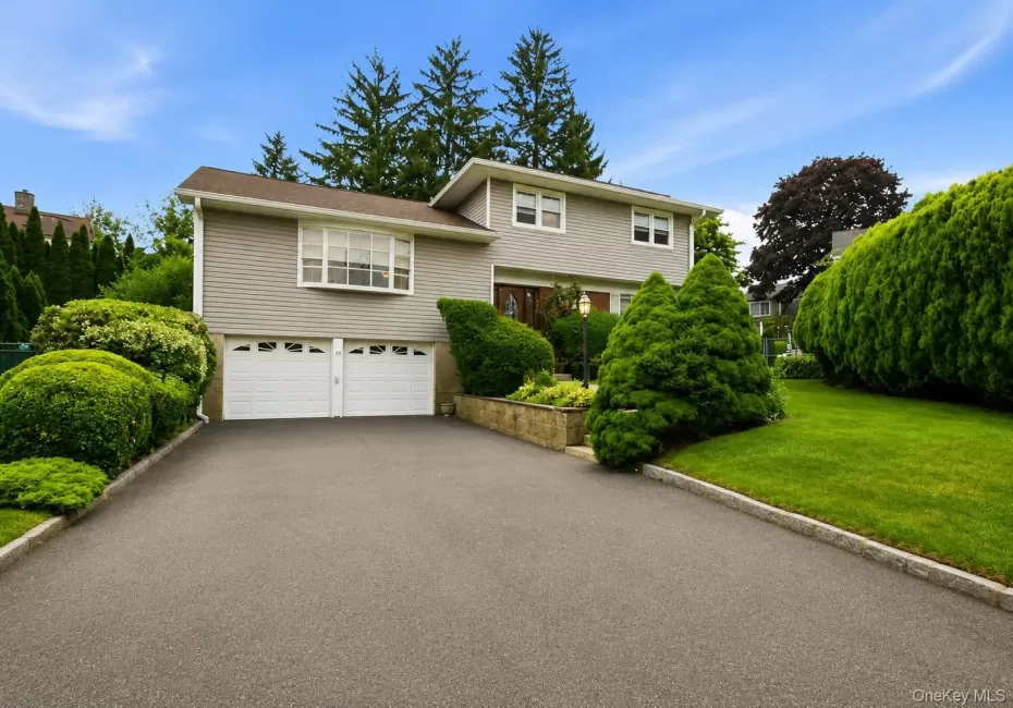 Split-level residence featuring light-colored siding and a two-car garage with white paneled doors Split-level residence featuring light-colored siding and a two-car garage with white paneled doors