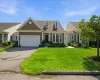 Ranch-style residence featuring a prominent stone facade, an attached two-car garage, and a gabled roofline with dormer windows Ranch-style residence featuring a prominent stone facade, an attached two-car garage, and a gabled roofline with dormer windows