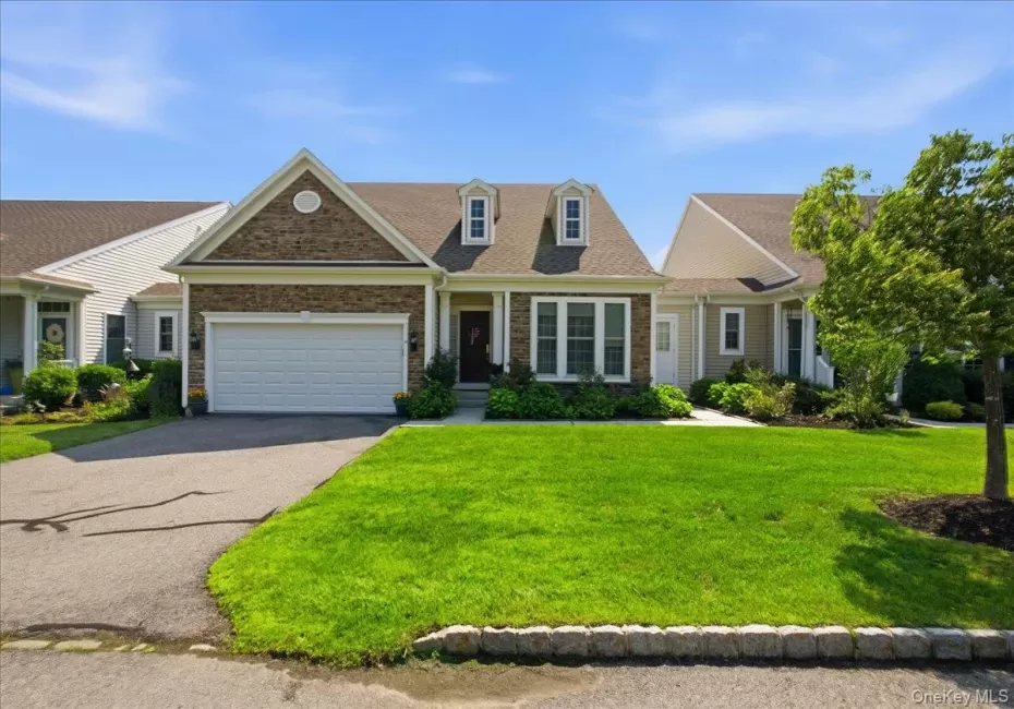 Ranch-style residence featuring a prominent stone facade, an attached two-car garage, and a gabled roofline with dormer windows Ranch-style residence featuring a prominent stone facade, an attached two-car garage, and a gabled roofline with dormer windows