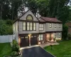 Two-story residence featuring light-toned siding with dark trim, a red-toned roofline with skylights, and a brick facade accent Two-story residence featuring light-toned siding with dark trim, a red-toned roofline with skylights, and a brick facade accent