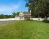 View of front of house with covered porch, driveway, a chimney, and view of scattered trees View of front of house with covered porch, driveway, a chimney, and view of scattered trees