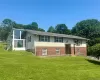 Split foyer home with a front yard, brick siding, and a sunroom Split foyer home with a front yard, brick siding, and a sunroom