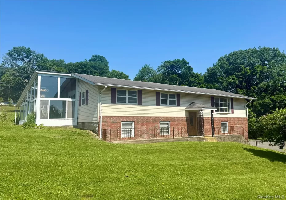 Split foyer home with a front yard, brick siding, and a sunroom Split foyer home with a front yard, brick siding, and a sunroom