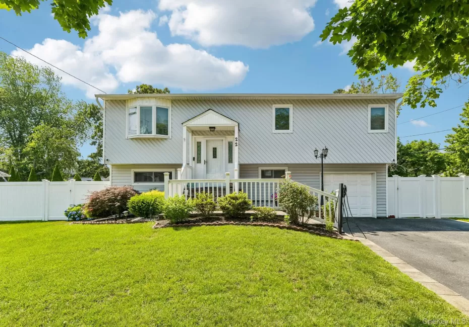 Split-level residence featuring light gray siding, a prominent bay window, and a covered entry porch Split-level residence featuring light gray siding, a prominent bay window, and a covered entry porch