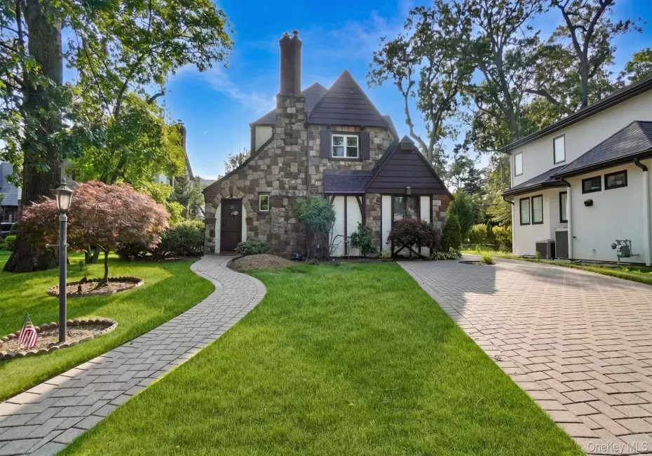 Stone facade residence featuring a prominent chimney structure and dark wood trim accents Stone facade residence featuring a prominent chimney structure and dark wood trim accents