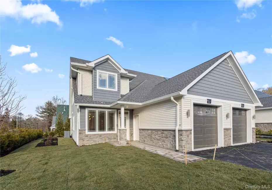 View of front facade with roof with shingles, stone siding, an attached garage, asphalt driveway, and a front lawn View of front facade with roof with shingles, stone siding, an attached garage, asphalt driveway, and a front lawn