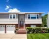 Split-level home featuring a light gray shingle and red brick facade Split-level home featuring a light gray shingle and red brick facade