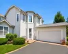Stucco exterior featuring multiple window styles, a prominent bay window, an attached two-car garage, and a paved driveway with brick edging Stucco exterior featuring multiple window styles, a prominent bay window, an attached two-car garage, and a paved driveway with brick edging