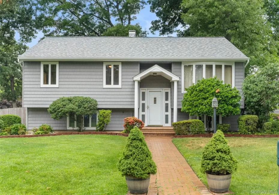 Gray shingle siding exterior featuring a covered entry, white front door, and bay window Gray shingle siding exterior featuring a covered entry, white front door, and bay window