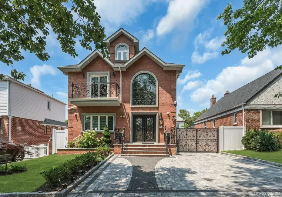 Brick face and side with a prominent elliptical window, double iron entry doors, and a second-story balcony with a decorative wrought iron railing Brick face and side with a prominent elliptical window, double iron entry doors, and a second-story balcony with a decorative wrought iron railing