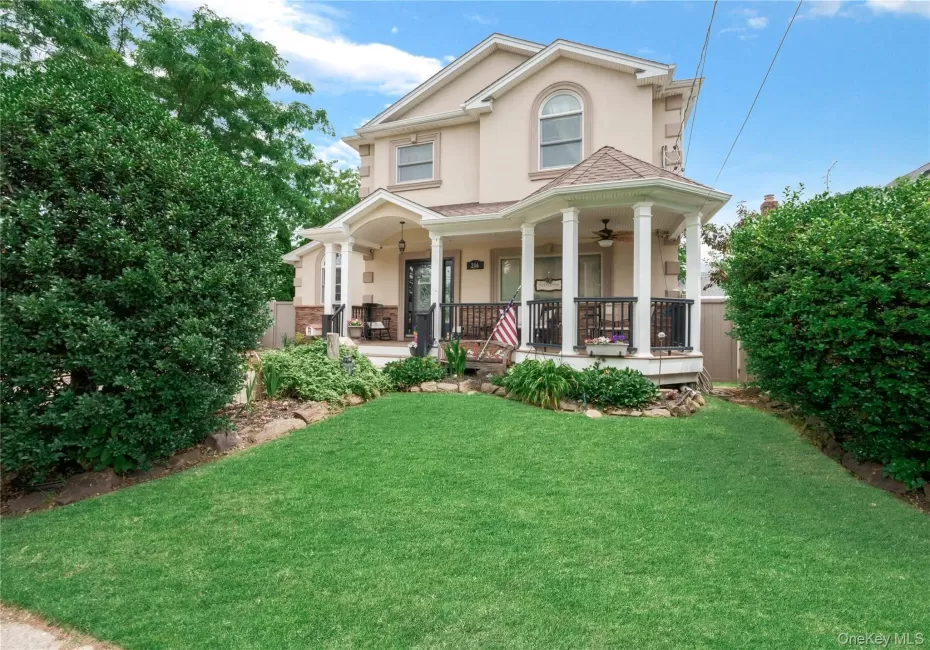 Stucco exterior with a columned porch featuring a ceiling fan and wrought iron railing Stucco exterior with a columned porch featuring a ceiling fan and wrought iron railing