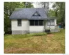 View of front of house featuring a shingled roof, a deck, a sunroom, and a front yard View of front of house featuring a shingled roof, a deck, a sunroom, and a front yard