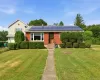 Brick facade home featuring solar panels and a landscaped front yard with a concrete walkway Brick facade home featuring solar panels and a landscaped front yard with a concrete walkway