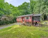 Raised ranch house featuring a red siding and brick facade, a screened-in porch, a paved driveway, and mature landscaping Raised ranch house featuring a red siding and brick facade, a screened-in porch, a paved driveway, and mature landscaping