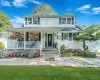White siding exterior featuring a covered front porch with white railings, a paver walkway, mature landscaping, and a dark front door with decorative glass White siding exterior featuring a covered front porch with white railings, a paver walkway, mature landscaping, and a dark front door with decorative glass
