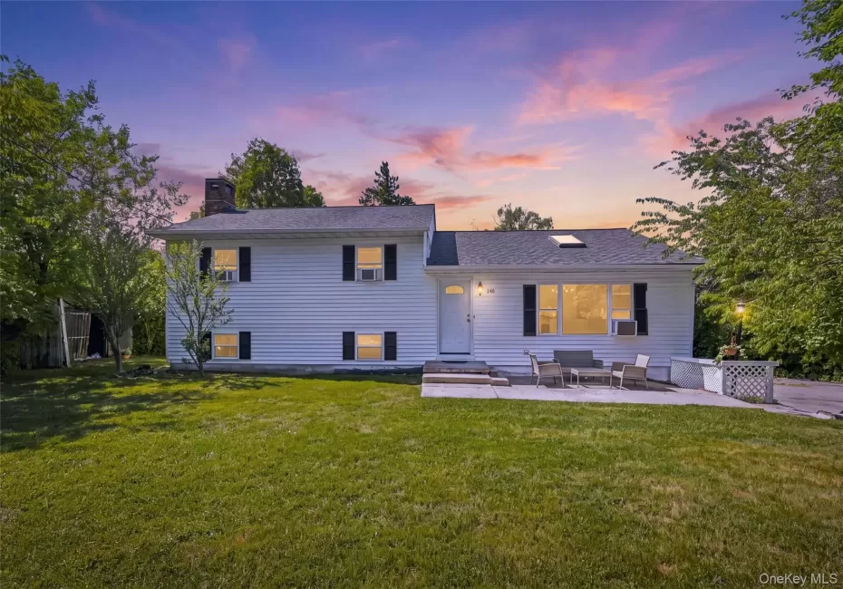 White siding residence featuring a prominent front lawn and a concrete patio White siding residence featuring a prominent front lawn and a concrete patio
