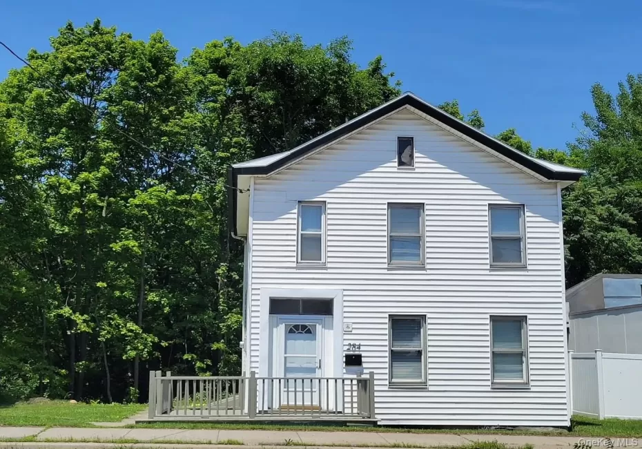 Two-story residence featuring white siding and a dark gabled roofline. Two-story residence featuring white siding and a dark gabled roofline.