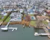 Waterfront property featuring a private boat dock, extensive rear decking, an in-ground swimming pool, and a manicured lawn Waterfront property featuring a private boat dock, extensive rear decking, an in-ground swimming pool, and a manicured lawn
