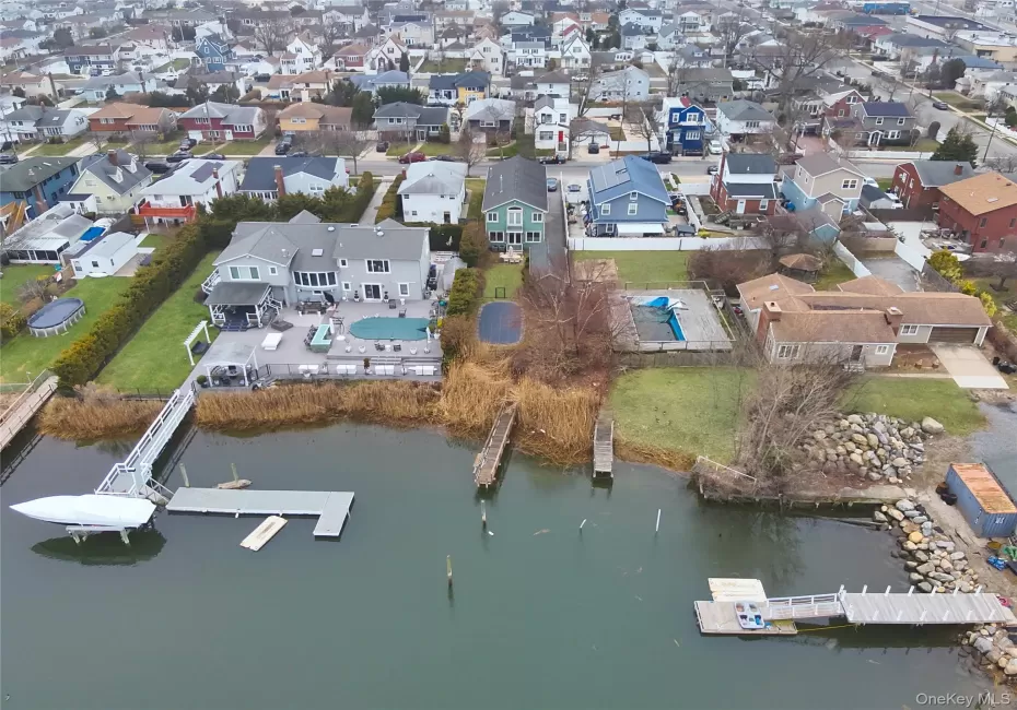 Waterfront property featuring a private boat dock, extensive rear decking, an in-ground swimming pool, and a manicured lawn Waterfront property featuring a private boat dock, extensive rear decking, an in-ground swimming pool, and a manicured lawn