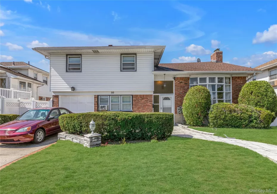 Tri-level home with brick siding, a front lawn, a chimney, and asphalt driveway Tri-level home with brick siding, a front lawn, a chimney, and asphalt driveway